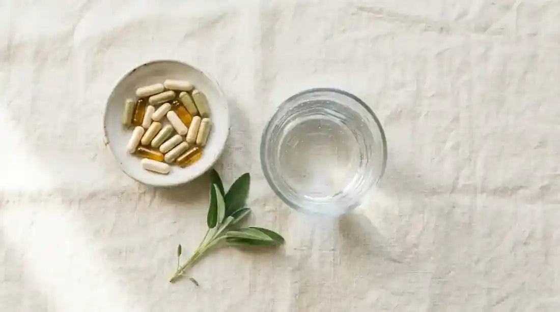 Supplement-Kapseln und Glas Wasser auf cremefarbenem Leinentuch, täglicher Frauenstack